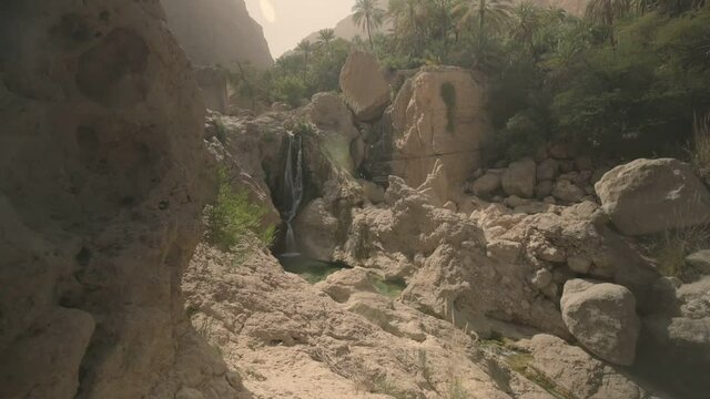 Barren Omani Desert narrow canyon with water creek and vegetation around it - Wide slide Reveal shot
