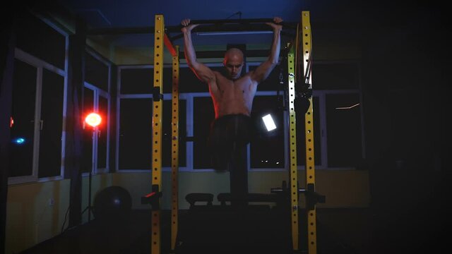 Young Man Performing Hanging Leg Raises Exercise For Abs