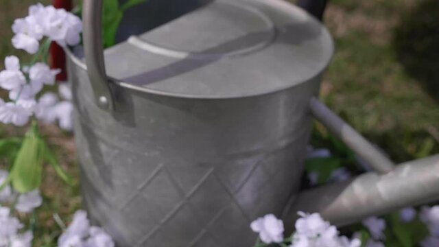 Galvanised metal watering can draped with flowers.