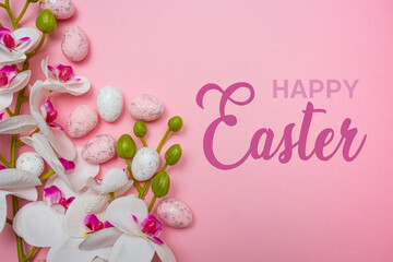 Colorful Easter eggs and flowers on pink background with happy Easter message. Spring holidays concept