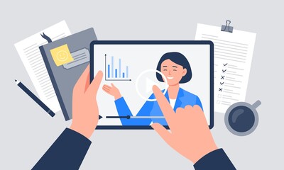 A workplace with coffee, notebook, papers, and tablet. A hand is holding a tablet with a video player. Vector flat illustration.