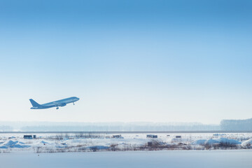 Fototapeta premium A passenger or cargo plane has left the runway and continues to climb in the air over a snow-covered winter airport