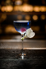 view on beautiful transparent glass with blue drink decorated with white flower