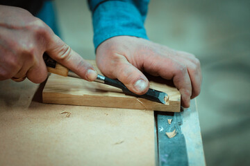 a man makes furniture, cutting details with tools