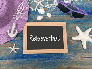 Tafel mit dem Text Reiseverbot und maritimer Dekoration.