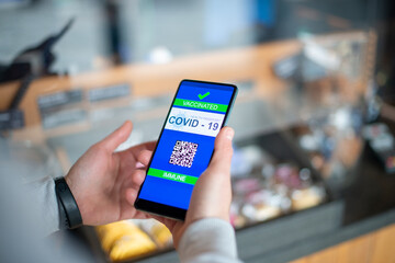 Man showing on smartphone covid imune certificate wich allow him to buy goods