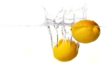 bright yellow lemons dropped in clear water