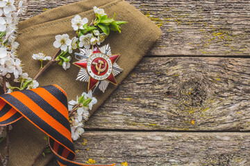 May 9, Victory Day holiday. Holiday card with order, St. George ribbon, flowers and military cap. May 9 background, copy space and translation with Victory Day.