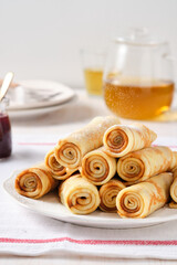 Crepes, thin pancakes with honey and tea on a white plate.