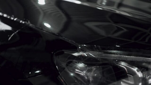 Close up of paint protection film installation on front bumper of modern luxury car. PPF is polyurethane film applied to car surface to protect the paint chips, bug splatter.