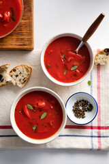 Tomato soup in a white bowl on white background. Top view. Copy space