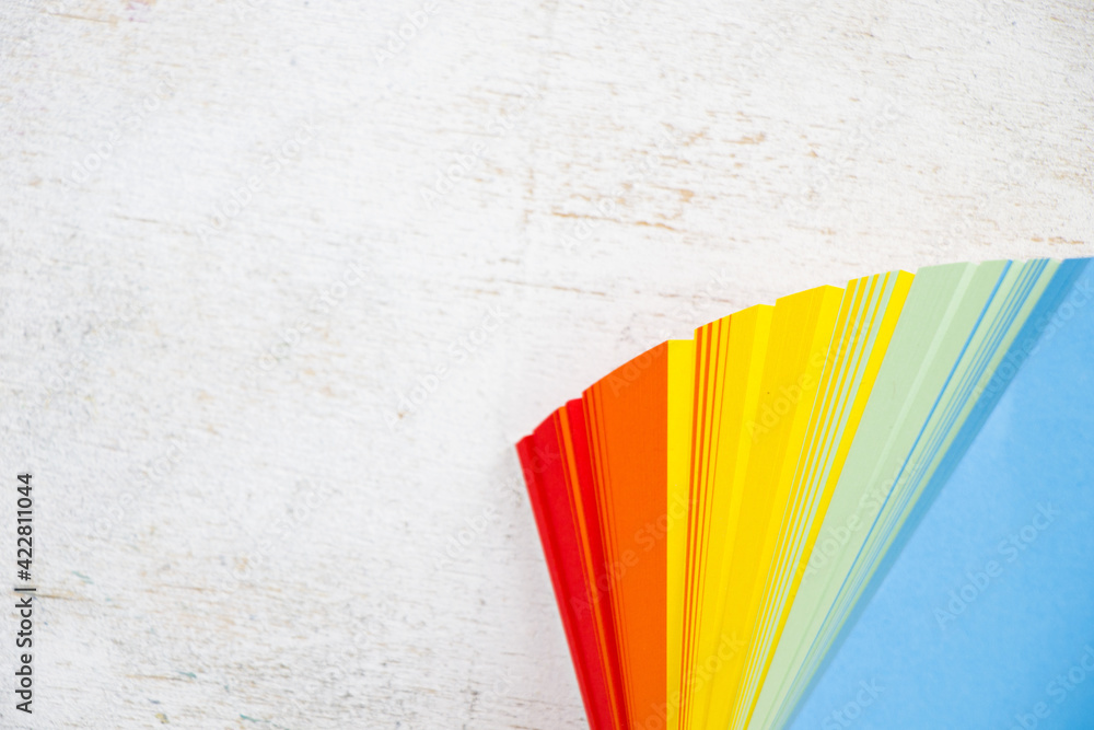 Poster overhead shot of a stack of colorful notepad on a white surface with space for your text