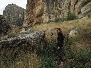 Obraz premium A woman in a black dress are walking in the mountains on nature in autumn