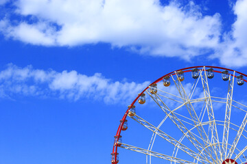 Ferris wheel on blue sky background. City attraction