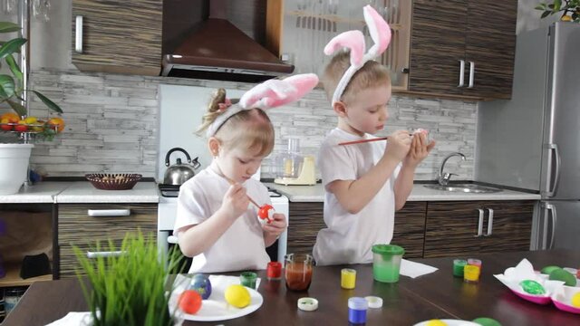 teenagers a boy and a girl in rabbit ears draw Easter eggs in the kitchen in preparation for the Easter holiday