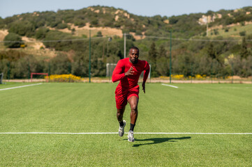 Fototapeta premium Black sportive speed runner, running in a football field.