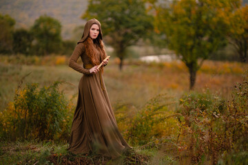 Redhead woman in dress walking in fantasy fairy tale forest