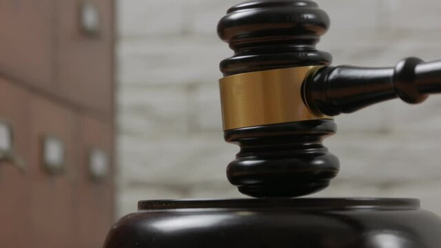 Close-up of a judge hitting a block with a hammer in a courtroom.