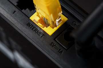Wireless modem router with yellow cable and LAN port for connection on a black background.