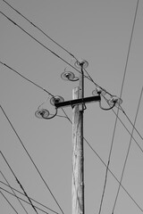 Old electrical pole with plugs and wires in sky background. BW photo