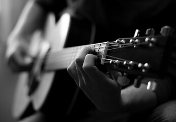 Young man playing acoustic guitar in black and white. Close-up