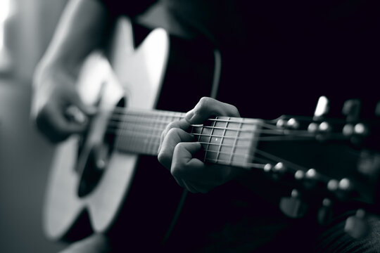 Young man playing acoustic guitar in black and white