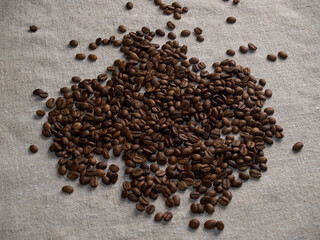 Roasted coffee beans scattered on a burlap napkin.