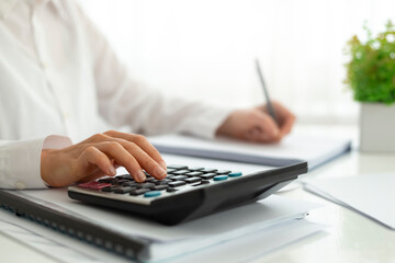 The financial analyst uses a calculator and notebook for the accounting report.