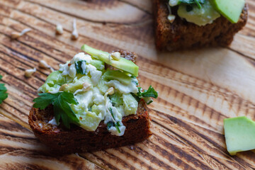 Sandwiches with green sprouted buckwheat, avocado, parsley and rye grain bread on a brown wooden table