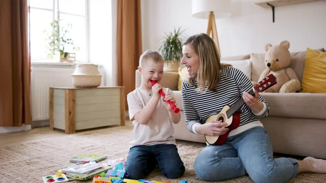 Single mother with down syndrome child at home, playing musical instruments.