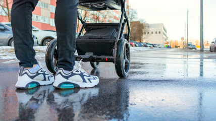 Fototapeta premium mom walks on the street with a baby in a stroller, stroller close-up, bottom view