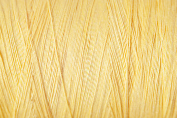 A macro shot of a spool of yellow thread.