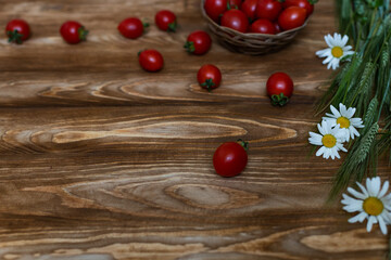 Naklejka na ściany i meble tomatoes in a basket on a wooden table with white chamomile flowers