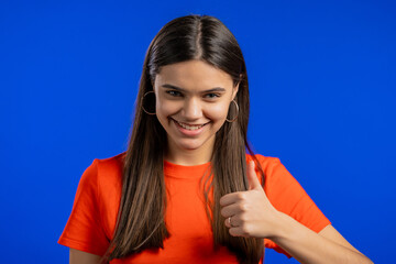 Woman showing Ok sign over studio background. Positive young girl smiles to camera. Winner. Success. Body language.