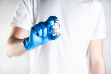 The doctor holds coronavirus vaccine in his hand. He has blue rubber gloves on his hands, which serve as protection against coronavirus infection.