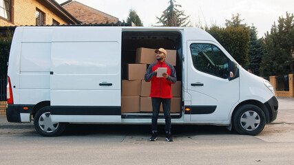 Young delivery man using tablet to find the address and deliver parcel. High quality photo