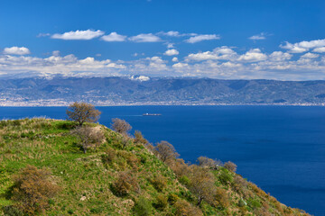Fototapeta premium panoramic view of the Messina strait in a particular spring day with blue sky and limpid coast of Calabria with splashes of snow on the hills