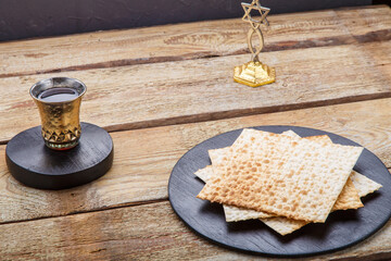 Fototapeta na wymiar On a wooden table matzah and a glass of wine for kiddush next to the menorah on the table.