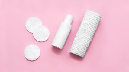 Makeup remover, cotton pads, white waffle towel isolated on pink background