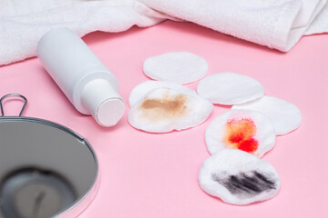 Obraz na płótnie Canvas Makeup remover, used cotton pads, portable mirror and white towel isolated on pink background