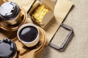 Fototapeta na wymiar Disposable paper tableware. Coffee cups in holder, cookie carton and paper bag