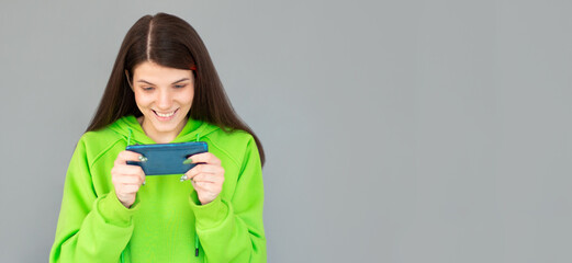 Shocked Woman in t-shirt which playing on phone. Isolated gray background