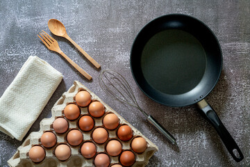 Still life with eggs and pan on wooden table, top...