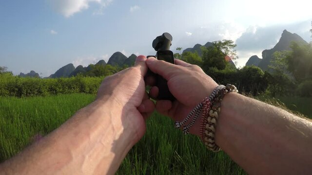Static view of backpacker filming with handheld stabilized gimbal camera in Yangshuo China popular chinese tourist destination for both foreign as domestic tourists area is known for mountain peaks