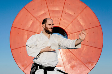 Caucasian man, wearing a karate kimono, with a red circle in the background. Karate, self-defense...