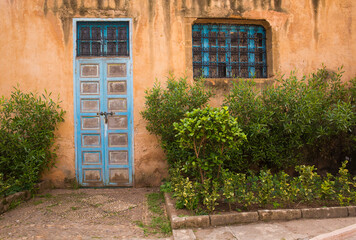 Fototapeta na wymiar Colorful, old, weathered building with lush, green foliage in Rabat, the capital of Morocco 