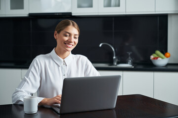 Positive woman using laptop while staying at home