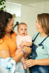 lesbian couple holding baby up in her arms .