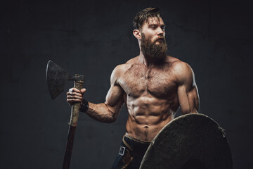 Northern warrior with axe and shield in dark background