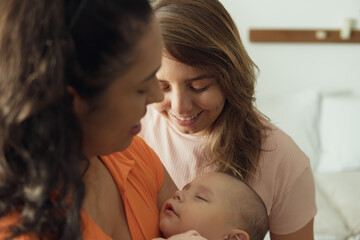 lesbian couple looking at sleeping baby in the living room.